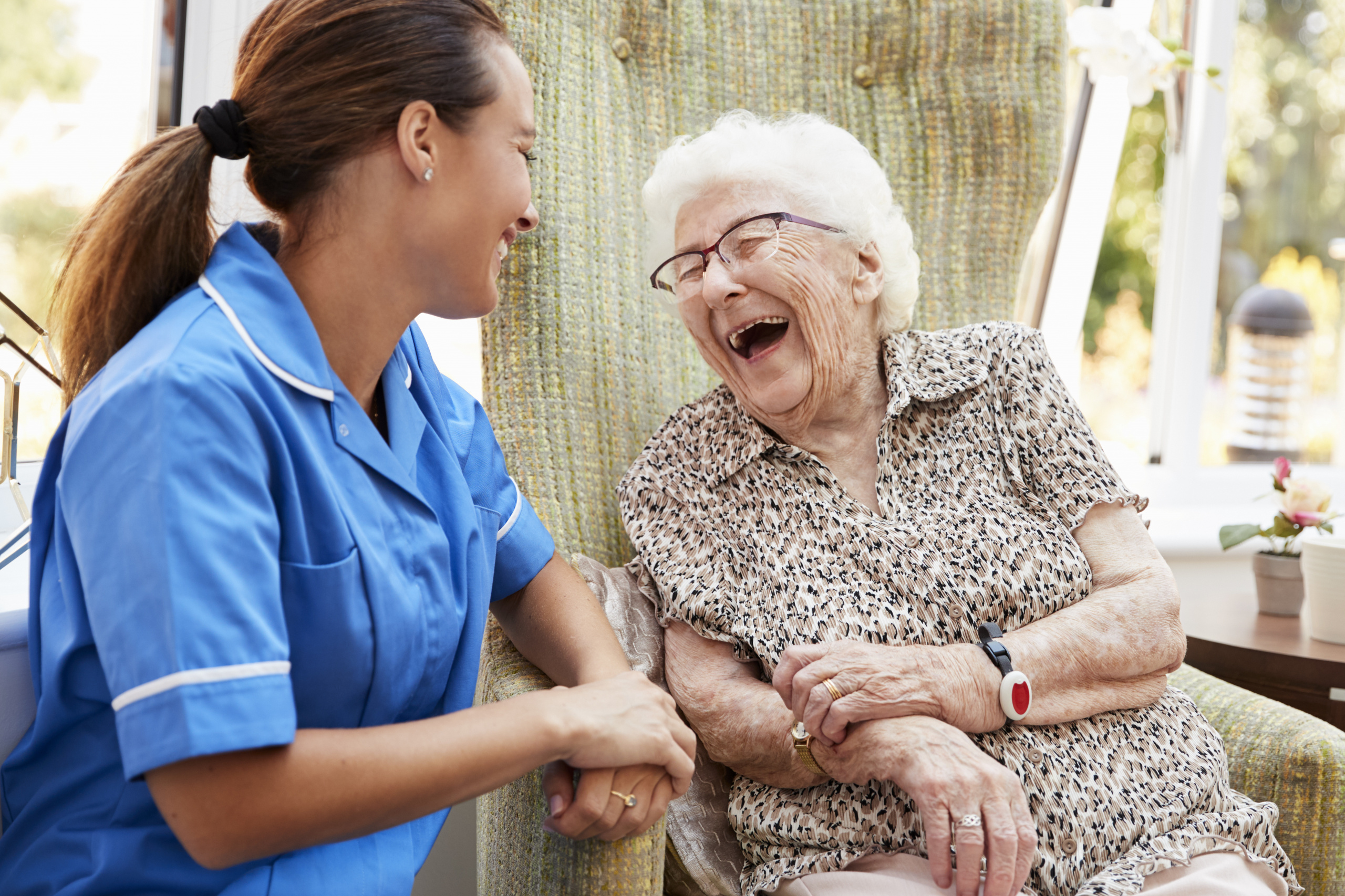 Illustrasjonsfoto. Helsepersonell og eldre dame ler sammen.